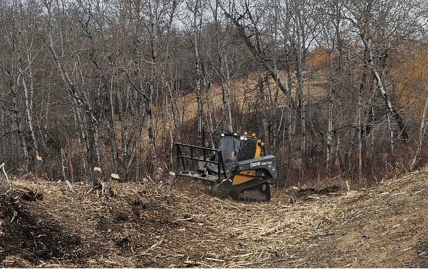 Skidsteer moves debris in a dry fall wooded area.
